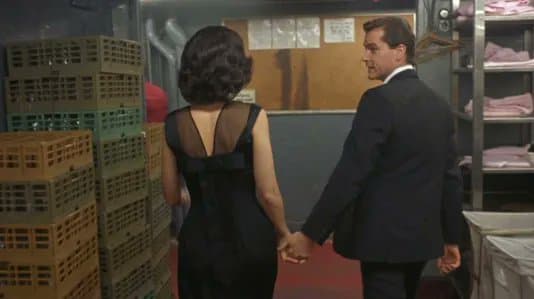 Goodfellas still: Henry Hill and Karen walk hand-in-hand through the Copacabana service corridor, captioned Cutting the line at the Copacabana.